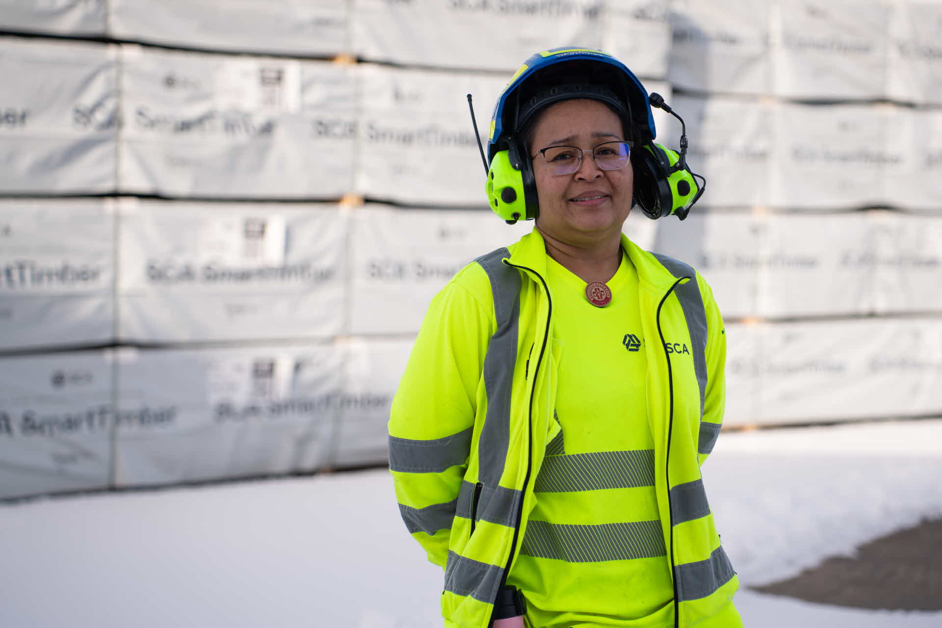 A portrait of Supranee in front of wood packages.