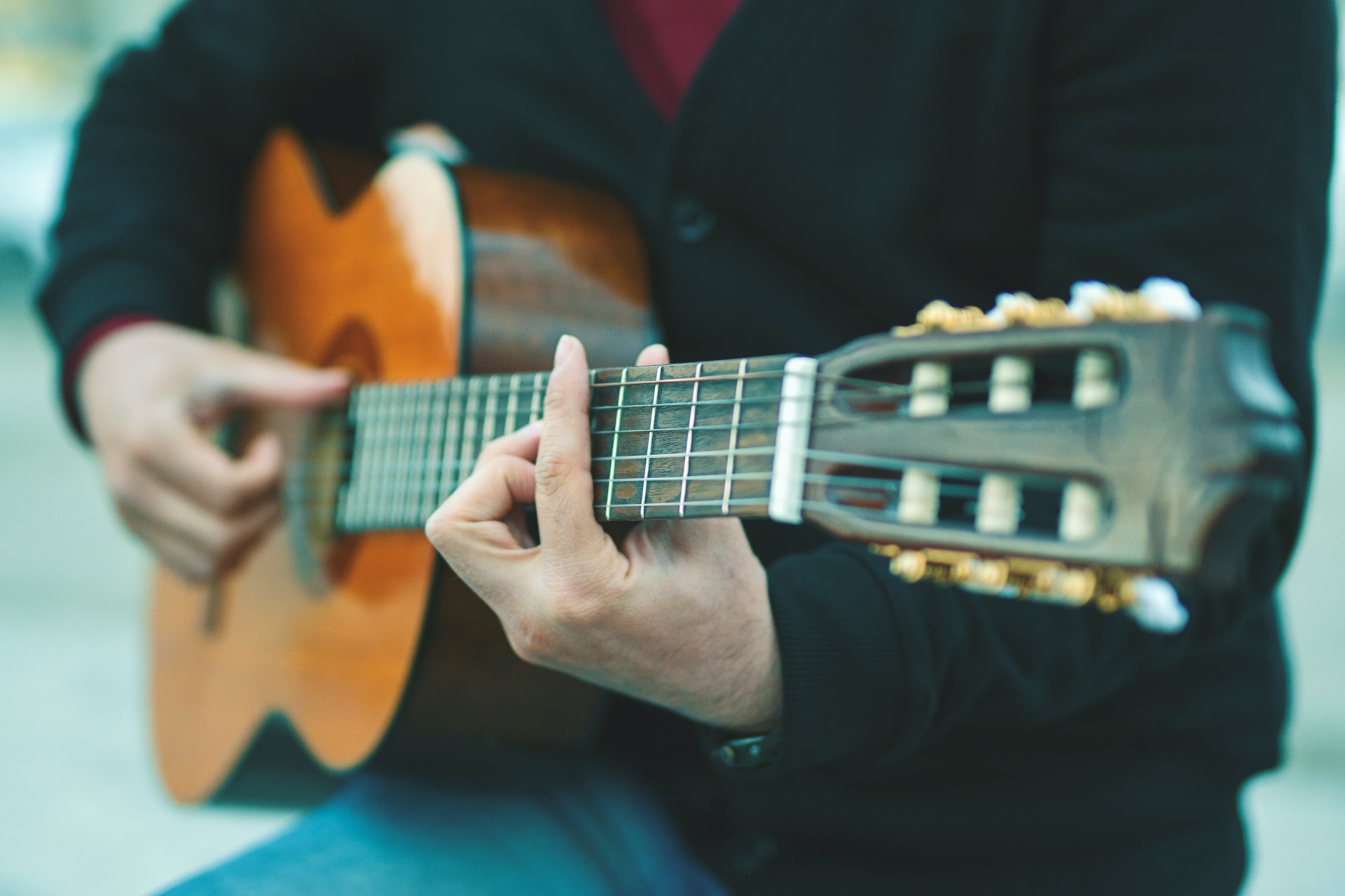 Person som spelar på en akustisk gitarr.