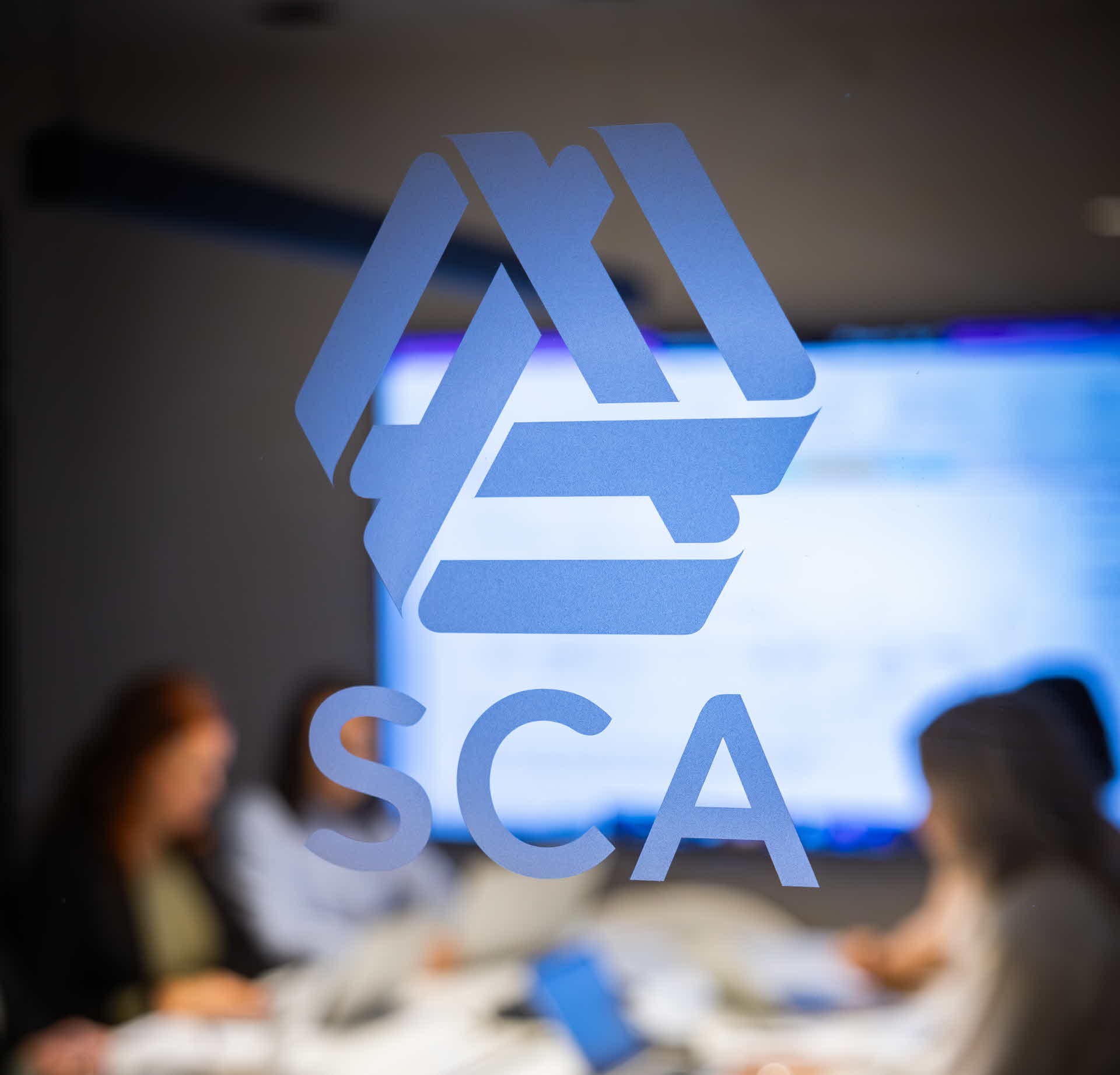 Sca-logotype och människor som arbetar i bakgrunden
