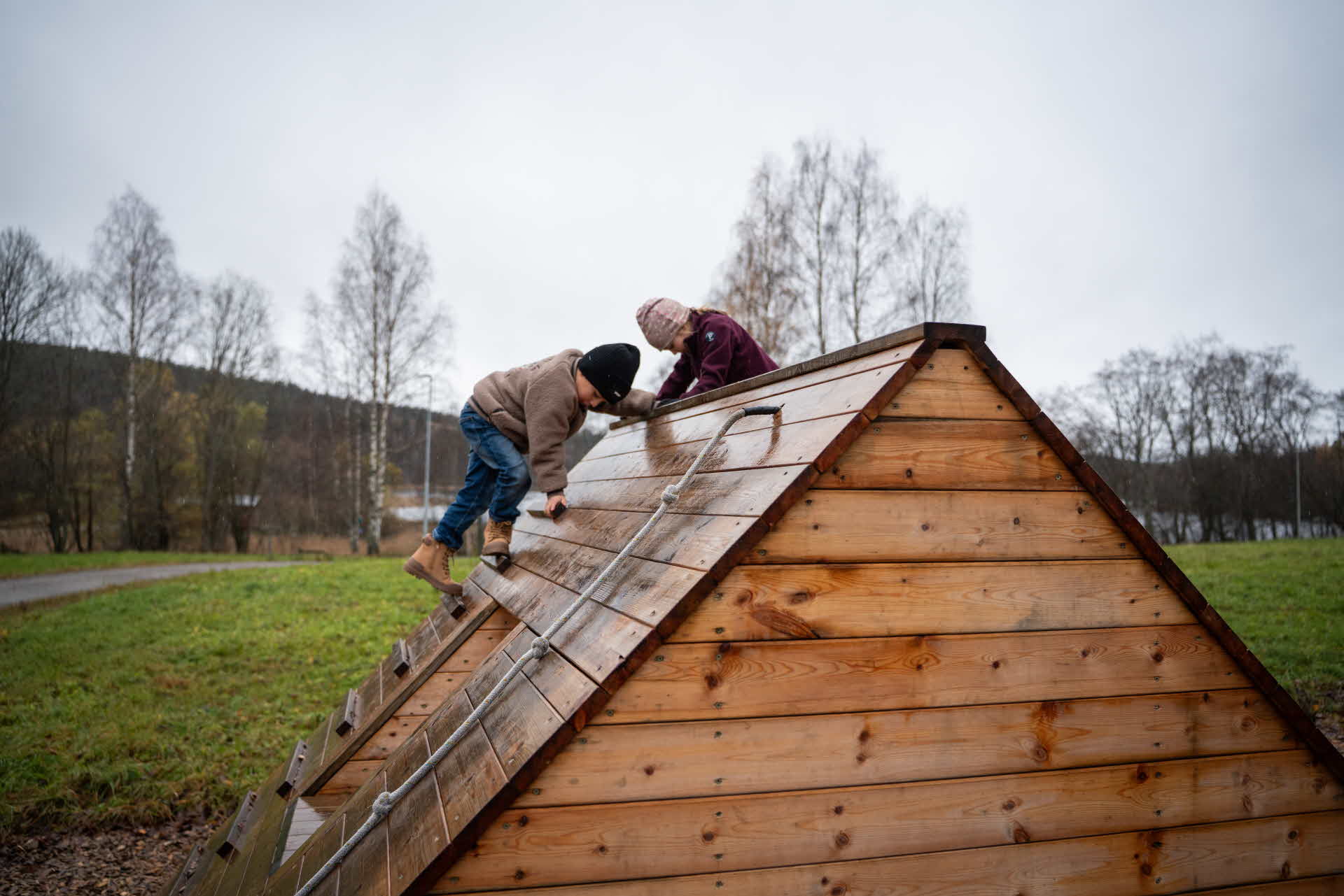 Två barn leker på en pyramid byggd i trä.