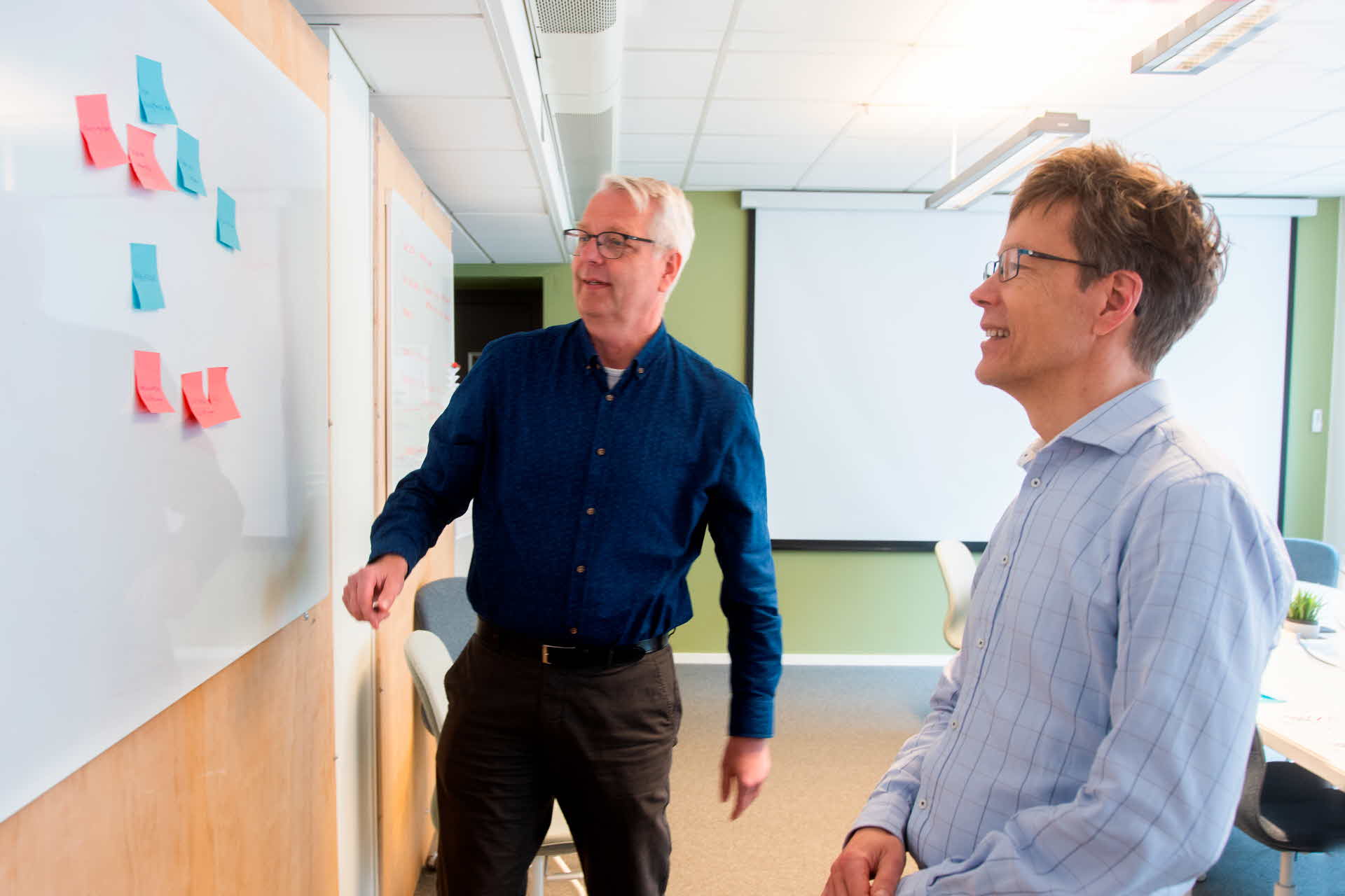 Two employees in front of a whiteboard.