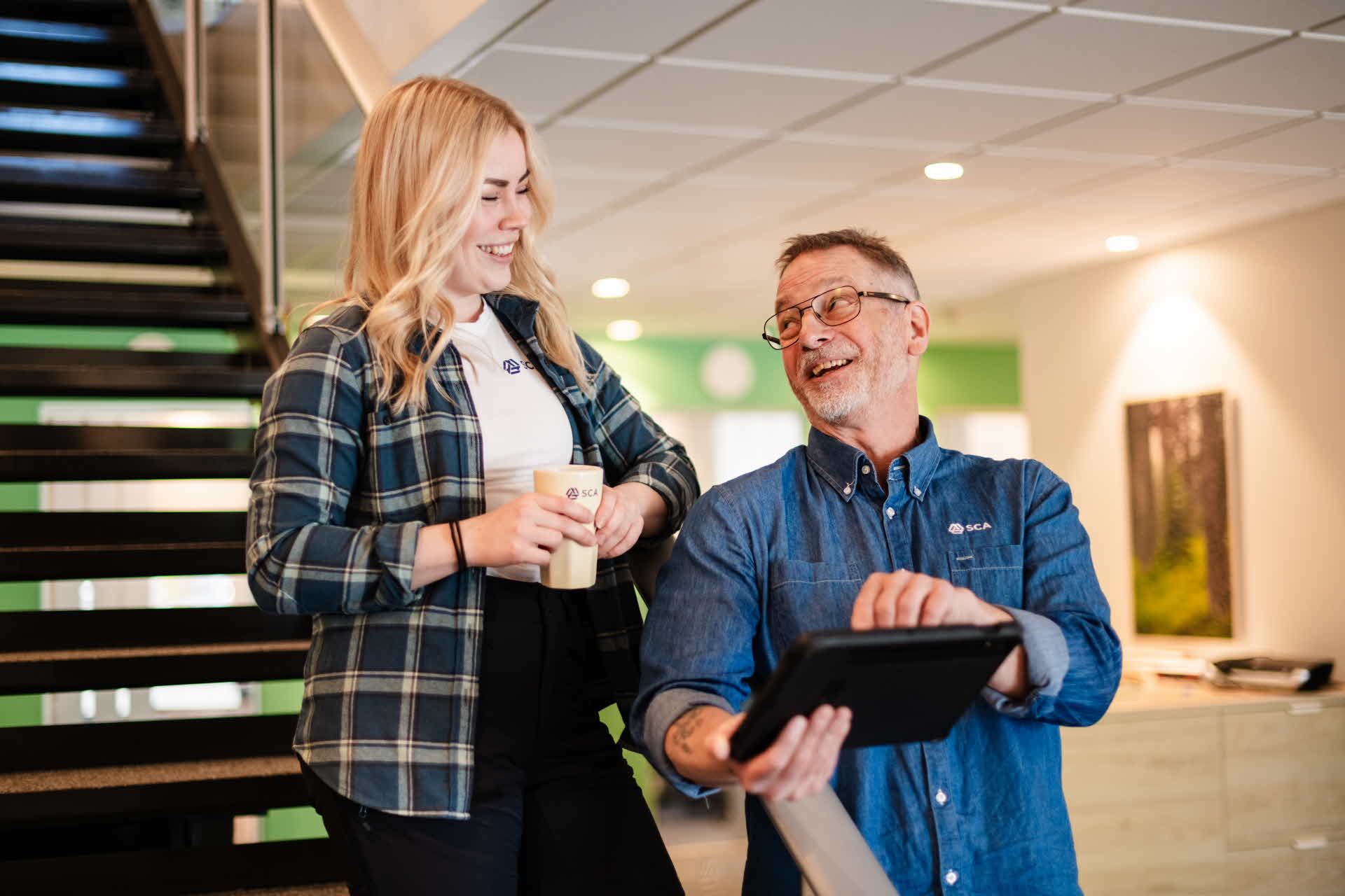 Halvkroppsbild på två glada medarbetare.
