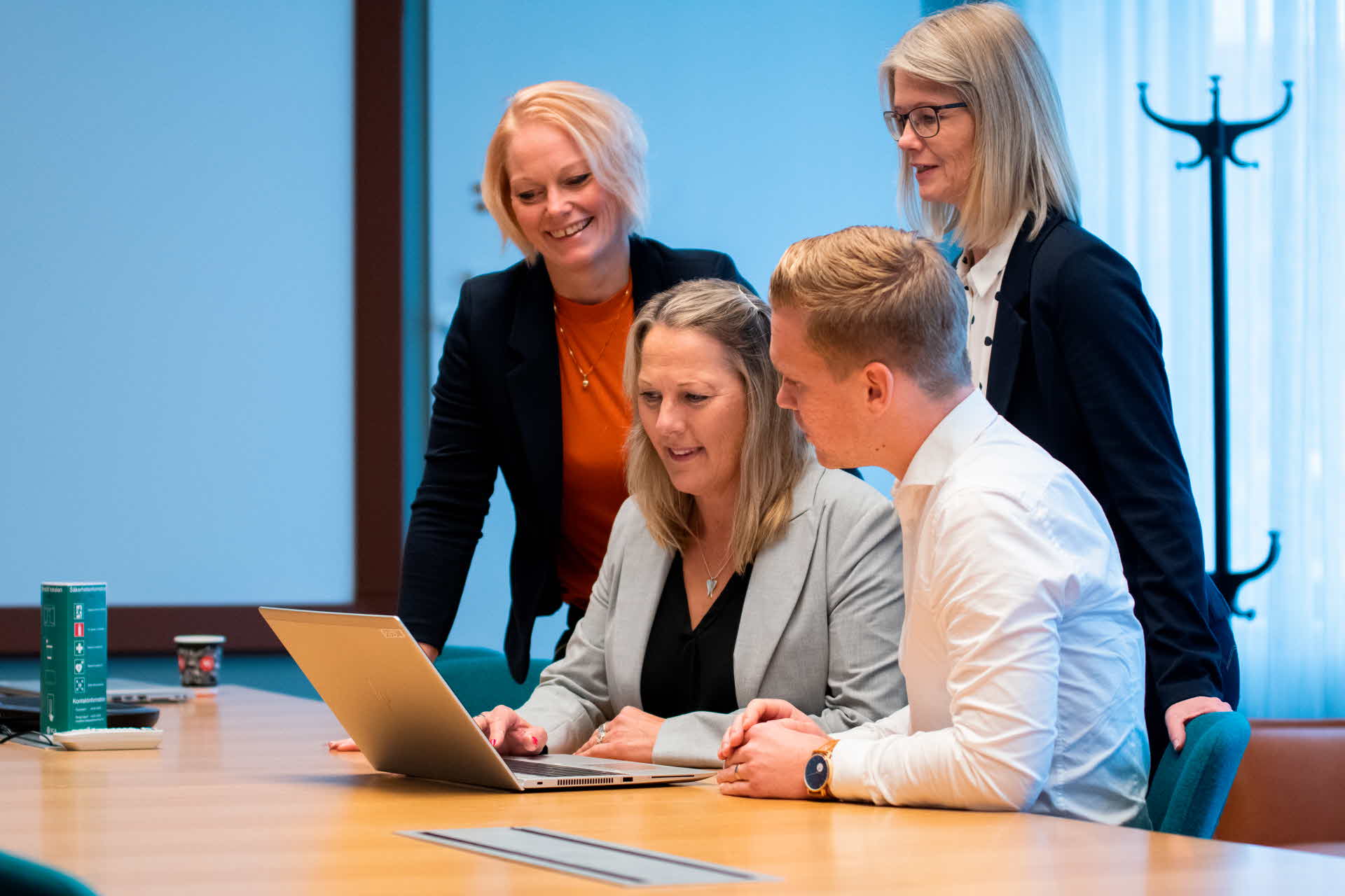 Four employees are looking at a computer screen.