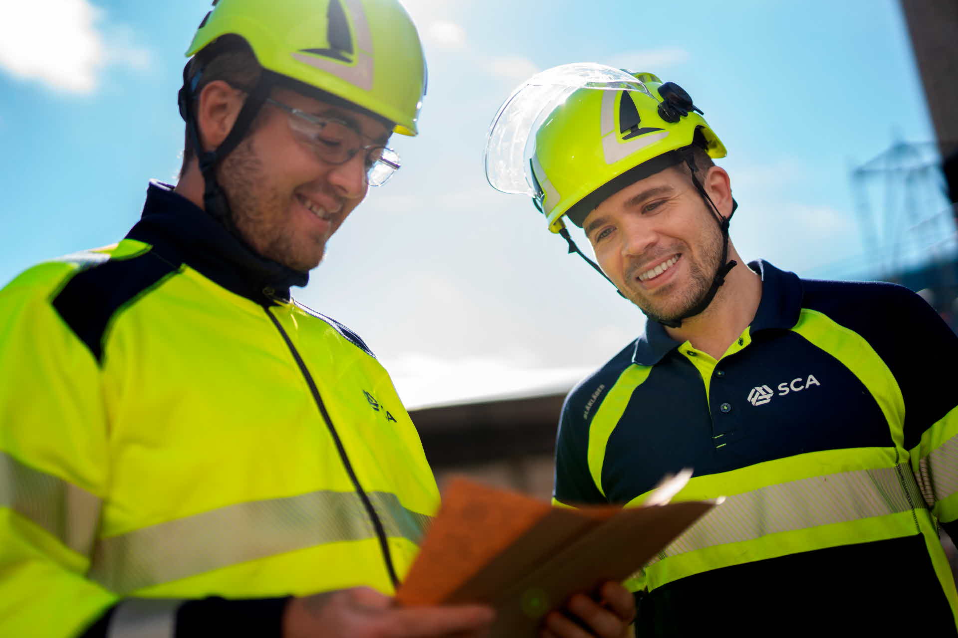 Close-up of two happy employees reading a note.