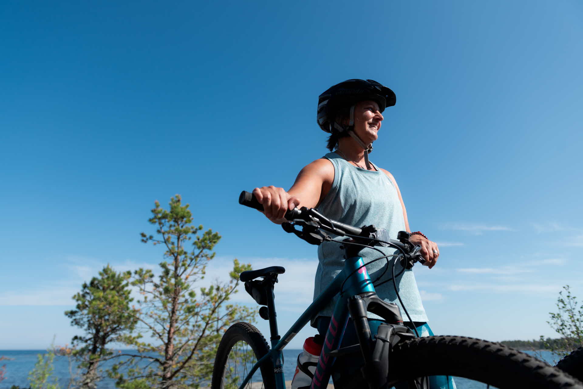 En person som håller i en cykel, havet syns i bakgrunden.