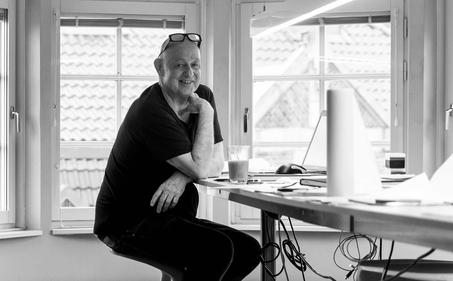 Gert Wingårdh sitter lent mot et skrivebord i et stort, lyst kontor.