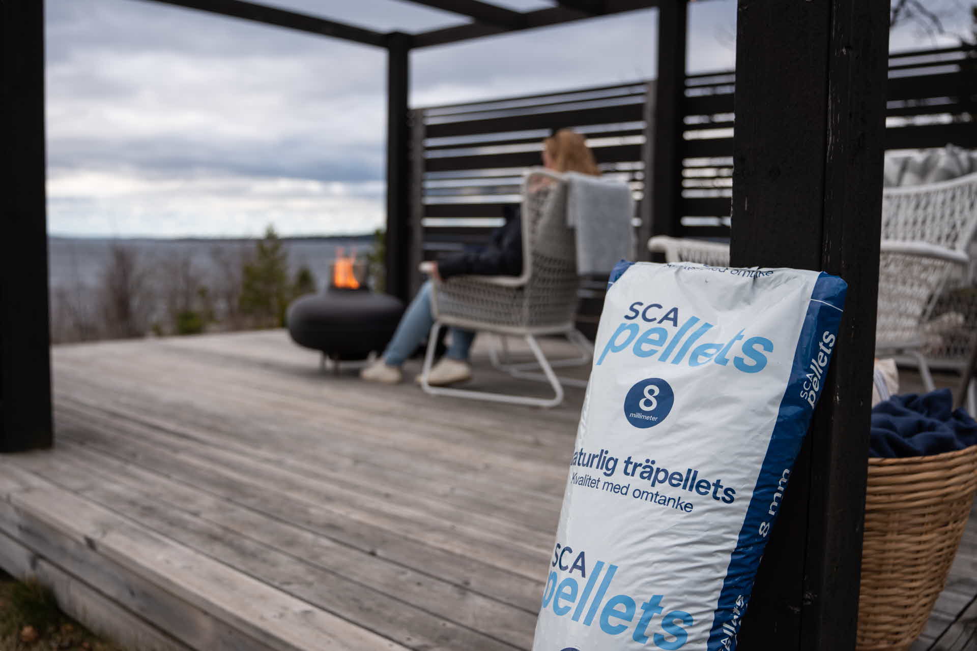 Pelletssäck lutad mot pergola där terassvärmare brinner med pellets