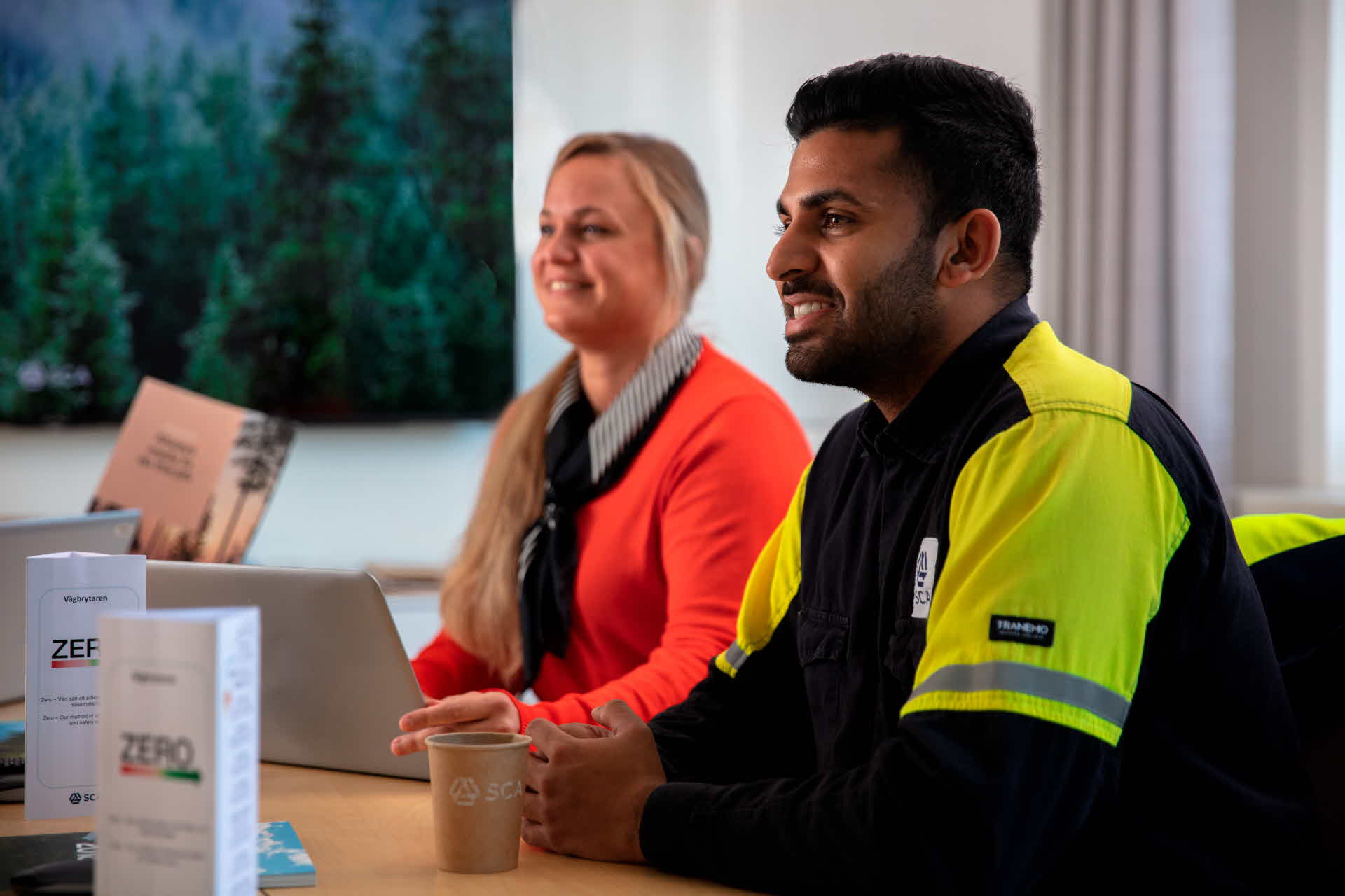 Two happy employees beside a table. 