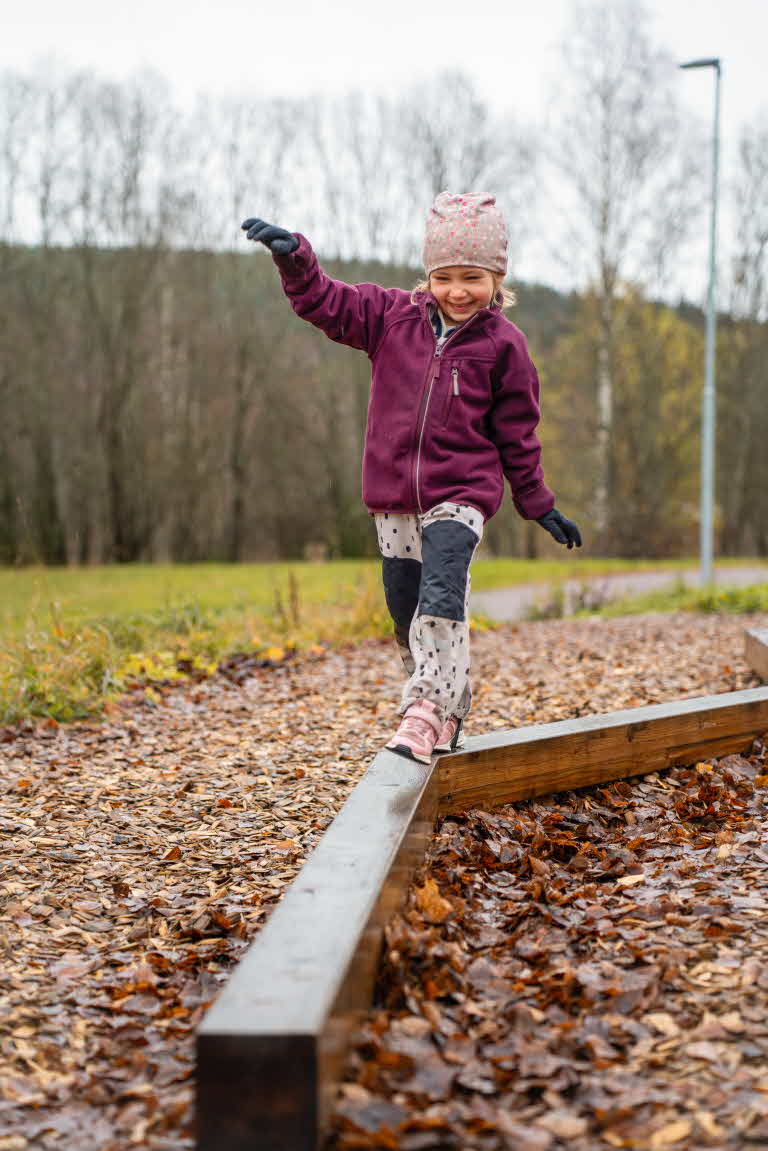 Ett barn balanserar på en balansgång.