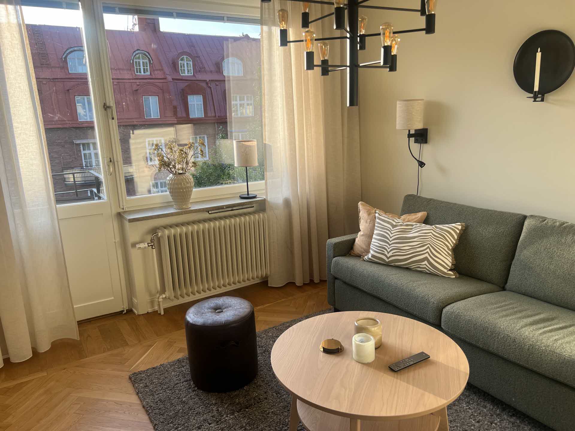 Ljust och modernt vardagsrum med en grågrön soffa.