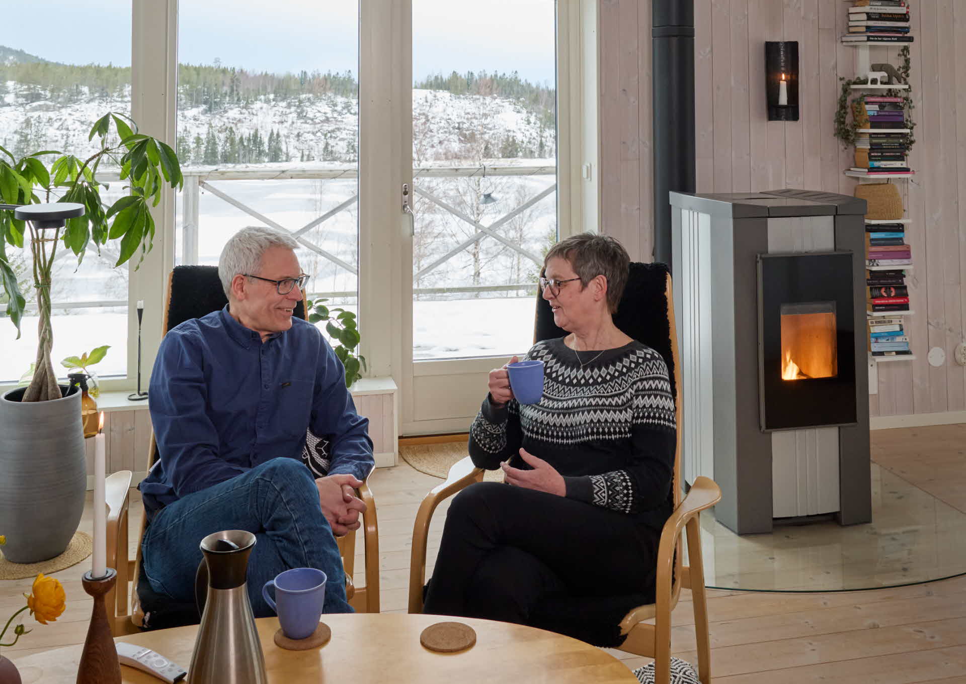 Lena och Nils dricker kaffe framför pelletskaminen