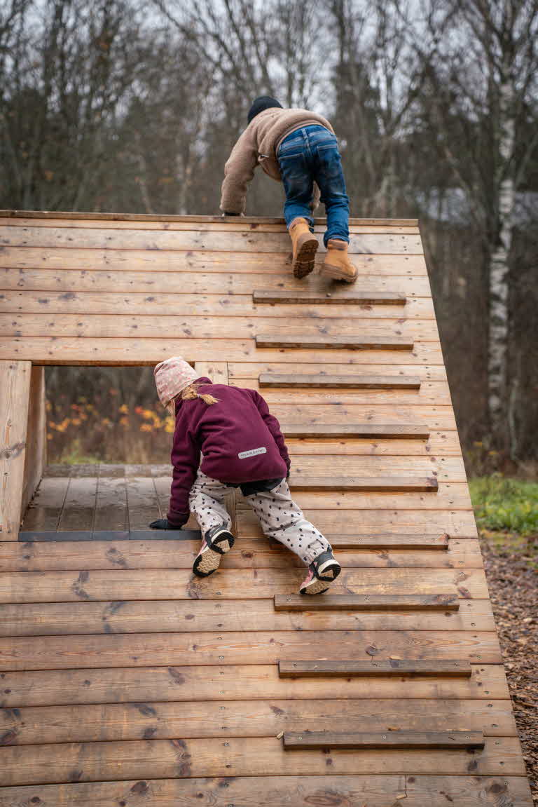 Barnen klättrar upp för träpyramiden.