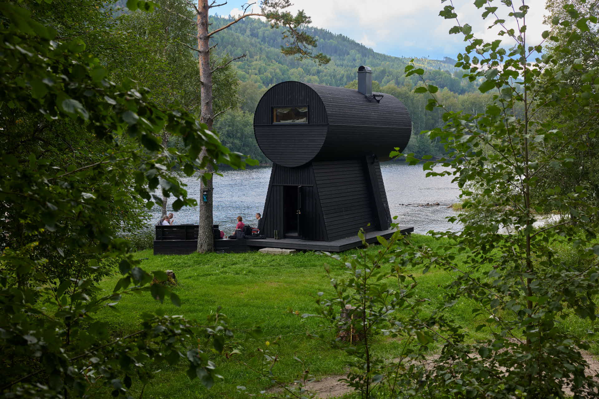 Exteriör bild på stugan zoominn i grönskan intill Indalsälven