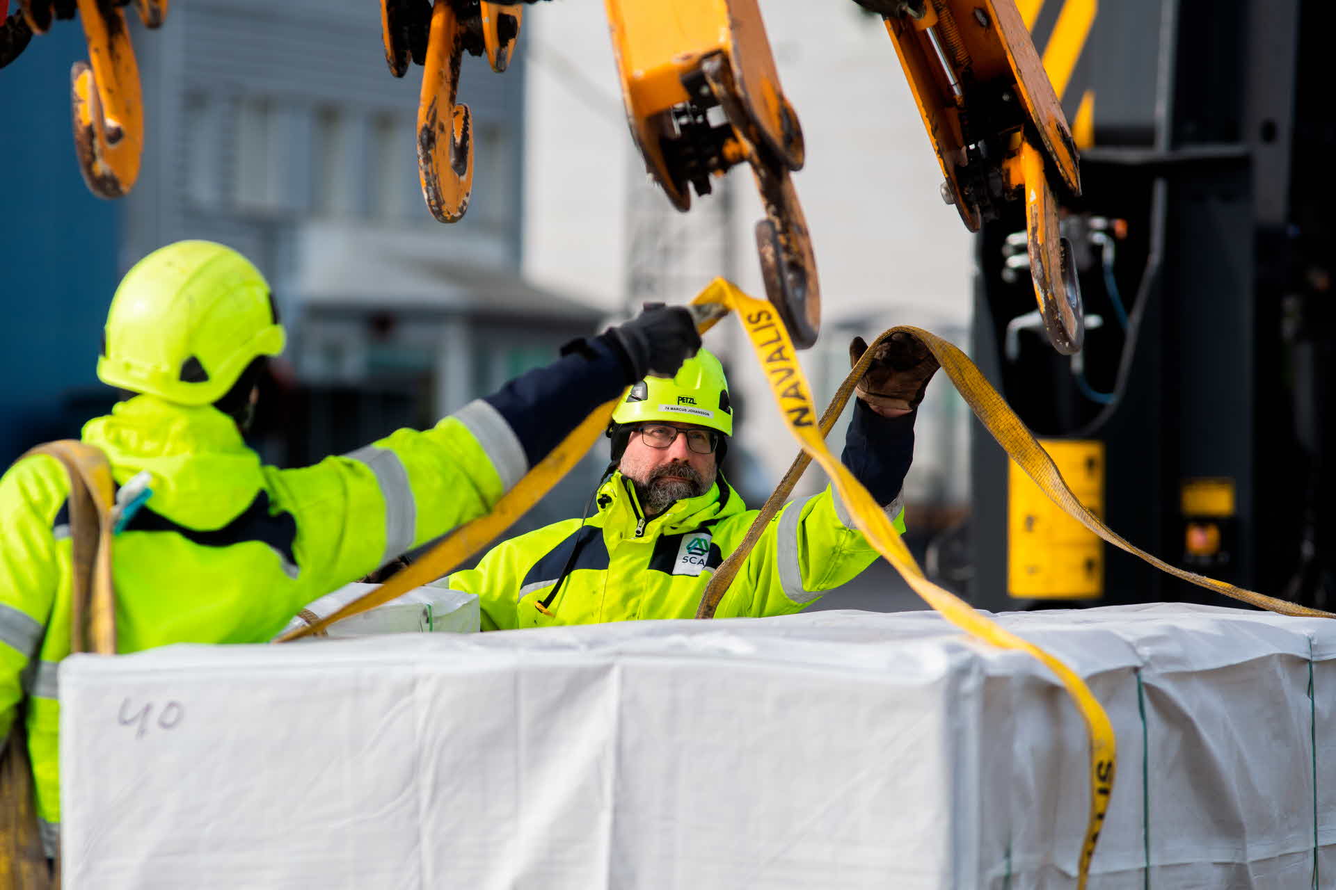 Två medarbetare lastar virkespaket för frakt.