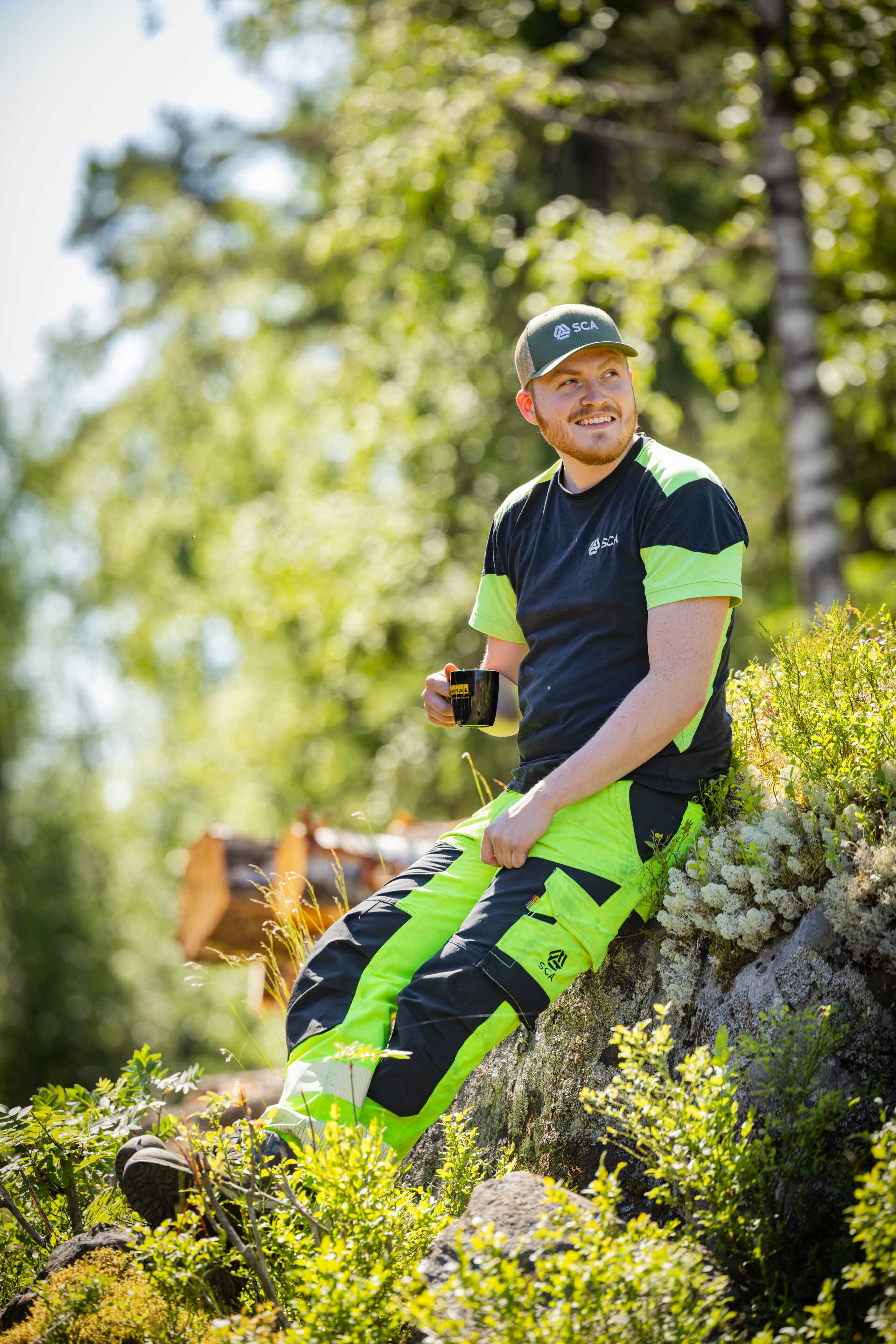 En man sitter och fikar på en sten i skogen