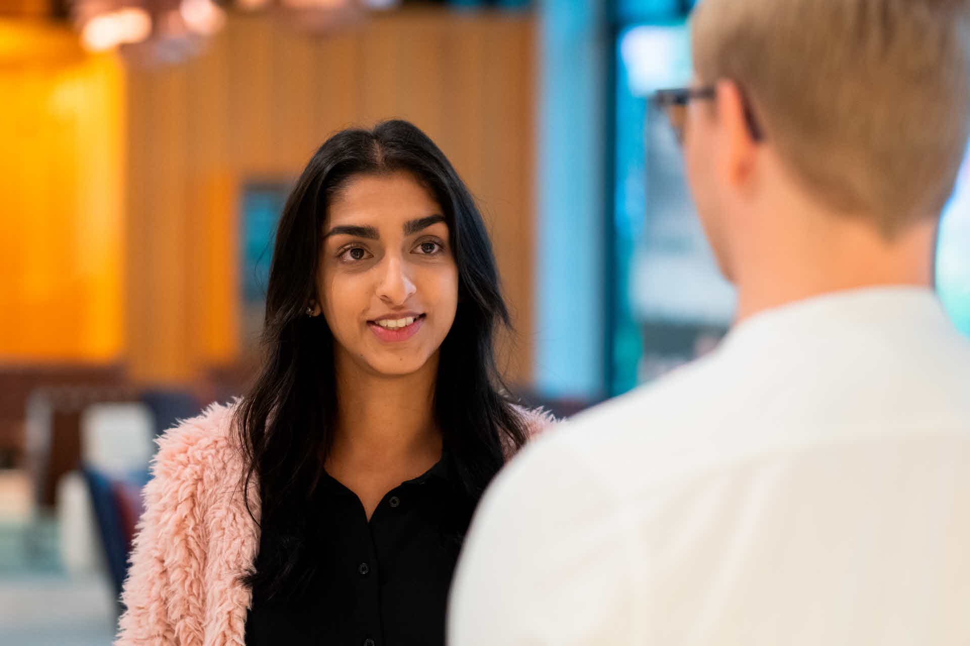 Close-up of a young female employee conversing with a male colleague.