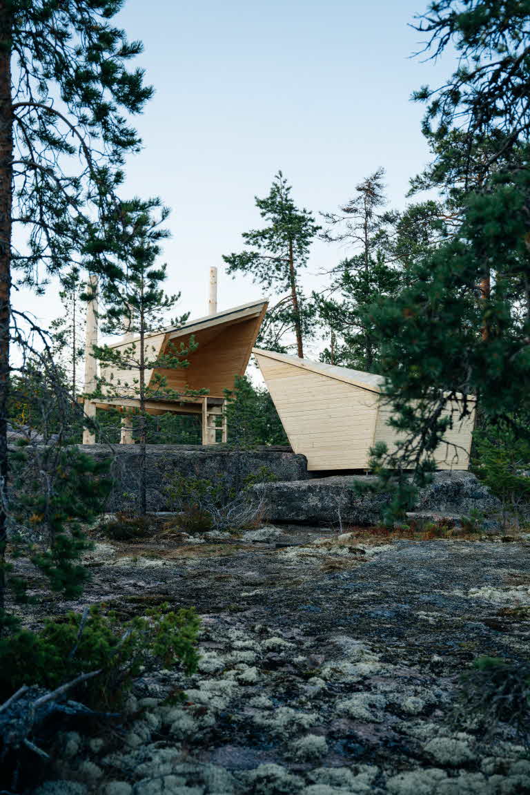 Två vindskydd placerade mitt emot varandra. Omringade av tallskog och stora stenblock.