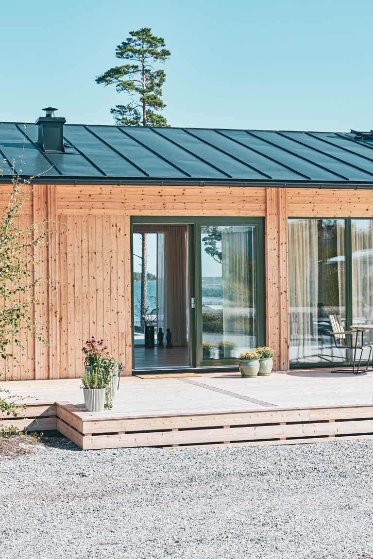 Ett trähus med stora glaspartier. Genom det stora glaspartiet syns havet på andra sidan.