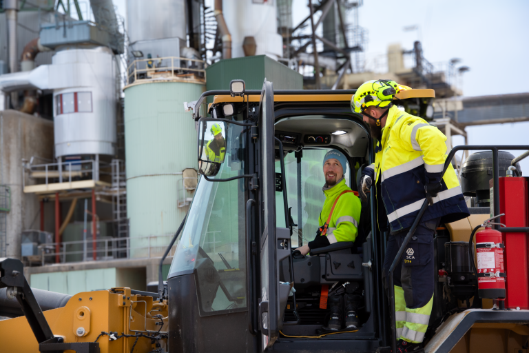 Operator and maintenance specialist in conversation in front of the pellet factory.